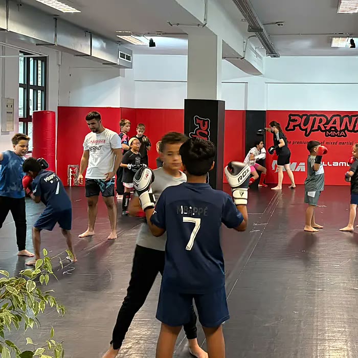 Selbstverteidigung für Kinder: Junge übt mit Handschuhen an den Pratzen des Trainers im Pyranha-Gym Offenbach