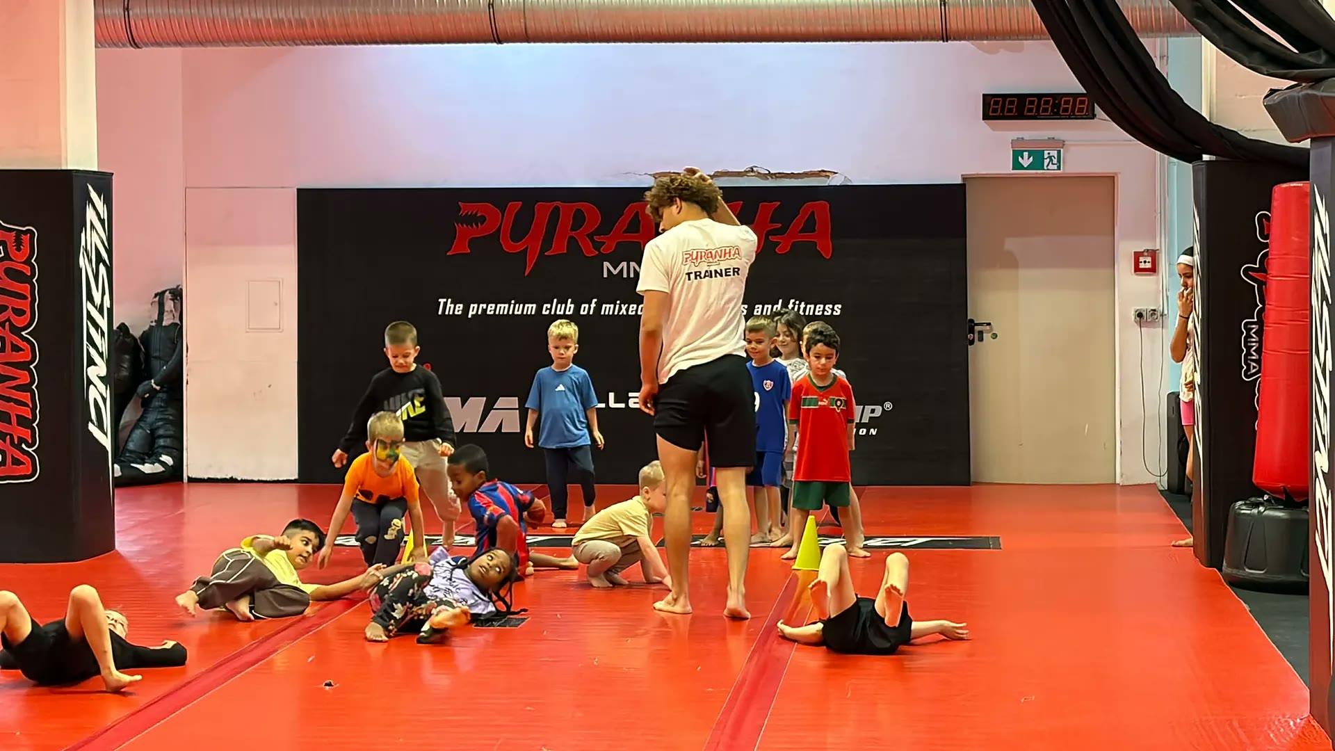 Kinder bei Bodenspielen mit dem Trainer auf der roten Matte